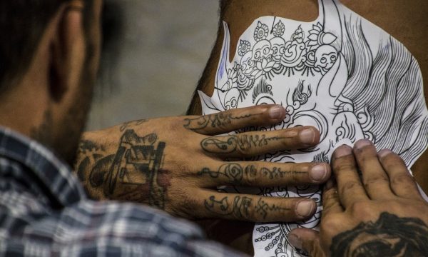 puntoycoma-estudio-tatuaje Se ve un tatuador poniendo en un brazo el papel para hacer el transfer en el cliente