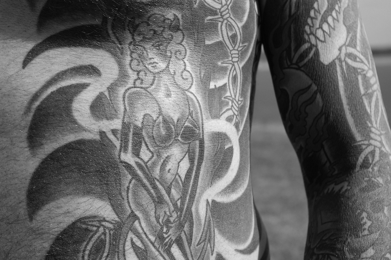 Se ve un pecho con una sirena tatuada. A la derecha se ve también un antebrazo que tiene mucho en color negro y un tatuaje de dientes de pantera estilo old school