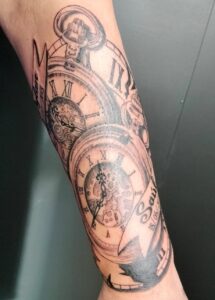 tatuaje de dos relojes antiguos donde se ve el nombre, la fecha y la hora del nacimiento de los nietos de nuestro cliente